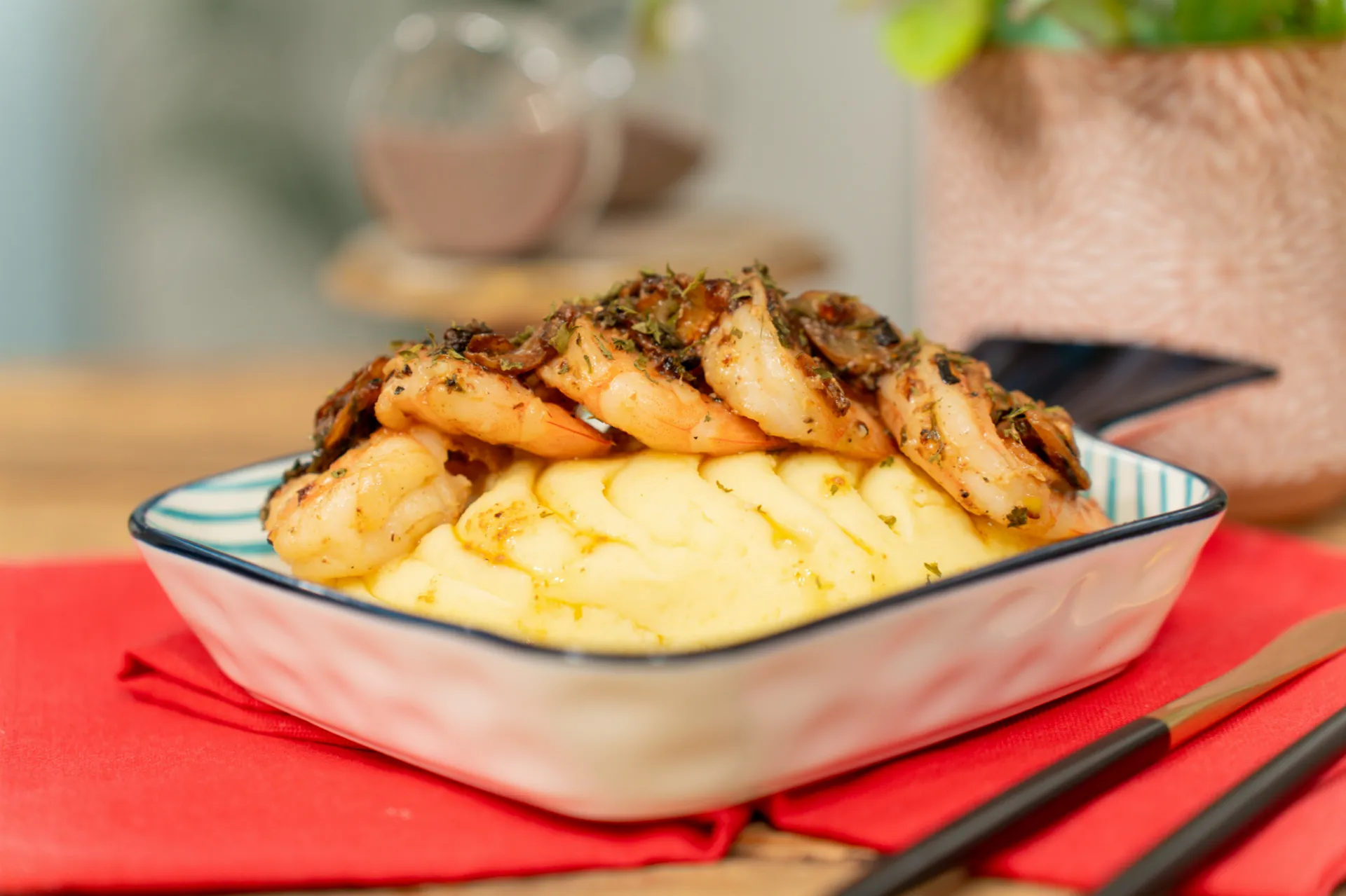 Camarones salteados sobre puré de papas en un plato blanco